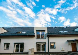 a white house with solar panels on the roof at Apartamenty Marynarki Wojennej, Dziwnów in Dziwnów