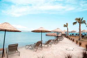 una fila de sillas y sombrillas en una playa en Cunda Fora Glamping en Ayvalık