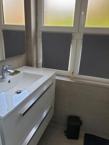 La salle de bains est pourvue d'un lavabo blanc et de 2 fenêtres. dans l'établissement le castor, à Deauville