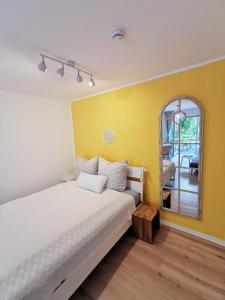 a bedroom with a white bed and a yellow wall at Lillys Apartment Kempten in Kempten