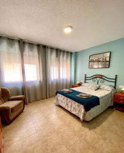 a bedroom with a bed and a chair at APARTAMENTO TURISTICO NAVALINDA in Casas del Monte