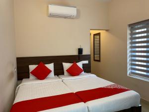 1 dormitorio con 1 cama grande con almohadas rojas en La Mer Inn, en Kozhikode
