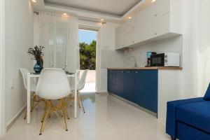 Una cocina con gabinetes azules y una mesa y sillas. en Čikat bay residence, en Mali Lošinj
