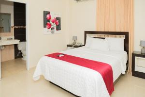 1 dormitorio con 1 cama blanca grande con manta roja en Hostal San Francisco de Asis en Santo Domingo