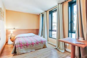 a bedroom with a bed and a table and windows at Hôtel Du Théâtre Centre Historique Parking Gratuit in Metz