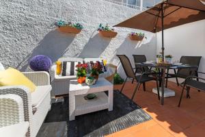 un patio con mesa, sillas y sombrilla en Casa Buganvília, en Cascais