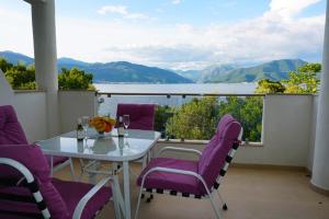 a table and chairs on a balcony with a view of the water at Apartmani M&E in Tivat