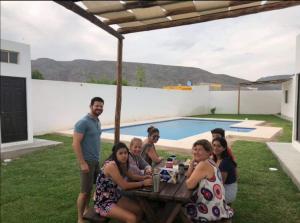 un grupo de personas sentadas en una mesa cerca de una piscina en Terra Viva Villa Campestre, en Cuatrociénegas de Carranza