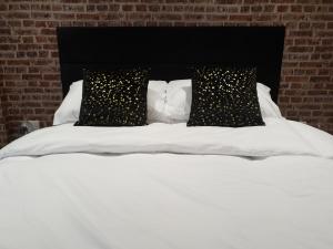 Una cama blanca con dos almohadas negras. en The Snug Bourne, en Bourne