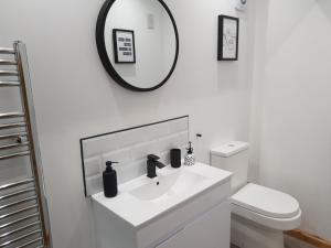 a white bathroom with a sink and a mirror at The Snug Bourne in Bourne