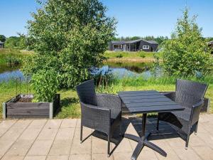 a table and chairs on a patio next to a lake at 8 person holiday home in Glesborg in Glesborg