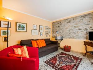 a living room with a red couch and a stone wall at Belvilla by OYO Casa Pascoso in Pescaglia