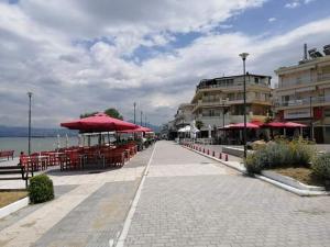 una strada con tavoli e ombrelloni rossi e un edificio di By the sea a Perea