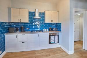 a kitchen with white cabinets and blue tiles at Host & Stay - Emerald Hideaway in Saltburn-by-the-Sea +7 photos