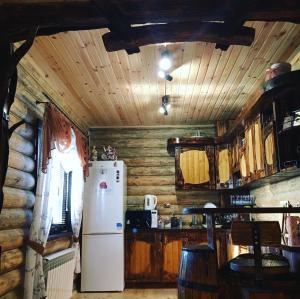 a kitchen with a white refrigerator and wooden walls at Woodhouse Svitiaz in Svityazʼ