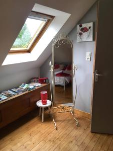 Dormitorio en el ático con espejo y cama en Les Coquelicots en Saint-Urbain