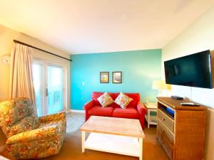 ein Wohnzimmer mit einem roten Sofa und einem TV in der Unterkunft Camelot by the Sea in St Pete Beach