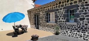 a table with a blue umbrella next to a building at Les perles vertes in Arlempdes