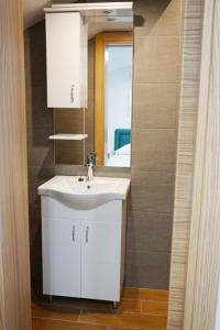 y baño con lavabo blanco y espejo. en Apartmani M&E en Tivat