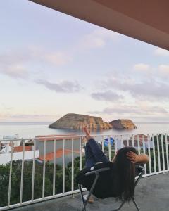 Eine Frau auf einem Stuhl auf einem Balkon mit Meerblick in der Unterkunft Apartamento Bela Vista Ilha Terceira in Feteira