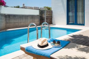 un sombrero sentado en un banco junto a una piscina en Anna Plakias Apartments, en Plakias