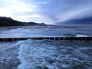 a body of water with waves and a pier at Villa Danusia in Ustronie Morskie