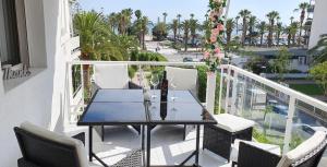 balcón con mesa, sillas y palmeras en Encantadora vivienda en el paseo marítimo de Salou, en Salou