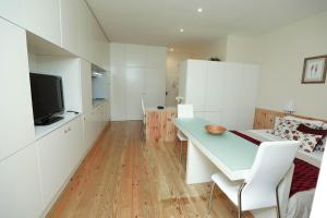 a living room with a table and a tv and white cabinets at M&M Space Apartments MM1 in Porto