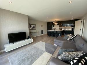 sala de estar con TV de pantalla plana y sofá en Principal Apartments - Clyde Waterfront Apartments, en Glasgow