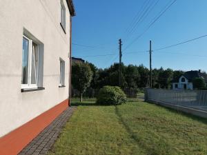 a side of a building with a grass yard at Apartament Leśny in Szczejkowice