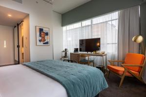 una camera con letto, scrivania e TV di The Muse Christchurch Art Hotel a Christchurch