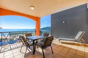 a dining room table with chairs and a balcony at Martinique Whitsunday Resort in Airlie Beach
