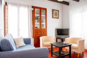 ein Wohnzimmer mit einem Sofa und zwei Sesseln und einem Fernseher in der Unterkunft Casa Boutique Margarita in Peñíscola