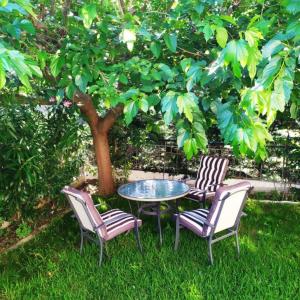 three chairs and a table in front of a tree at HOUSE WITH GARDEN Netflix in Néa Kerasiá