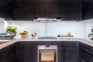 a kitchen with black cabinets and a stainless steel oven at Oakwood Residence Damei Beijing in Beijing