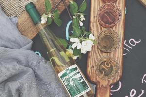 - une table en bois avec une bouteille de vin et des fleurs dans l'établissement Domaine Steinbach Cidrerie B&B Distillerie, à Saint-Pierre-de-l'Île-d'Orléans