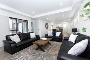 a living room with black leather furniture and a table at TWO TEN Sleeps 10! Luxury CBD Accommodation in Wagga Wagga