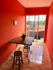 a table and stool in a room with red walls at Casa em Gravata mobiliada in Gravatá