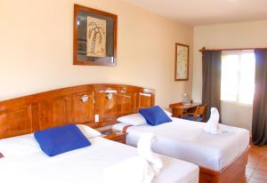 a hotel room with two beds with blue and white pillows at Hotel Angra in Loreto