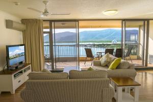 a living room with a couch and a television and a balcony at Cairns Aquarius in Cairns
