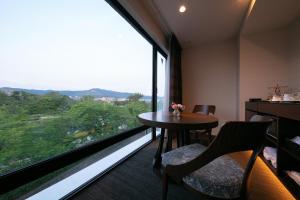 Cette chambre dispose d'une grande fenêtre et d'une table avec des chaises. dans l'établissement Riverte Kyoto Kamogawa, à Kyoto