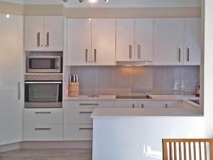 a kitchen with white cabinets and a stove top oven at Adriana 3 unit with a backyard in Shoal Bay