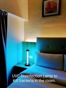 Habitación con cama y mesita de noche con lámpara en BIG M Hotel en Kuala Lumpur