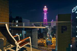 einen Stuhl auf einem Balkon mit Turm in der Nacht in der Unterkunft Montana Flat Yebisu in Osaka