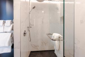 a bathroom with a shower with a glass door at The Muse Christchurch Art Hotel in Christchurch