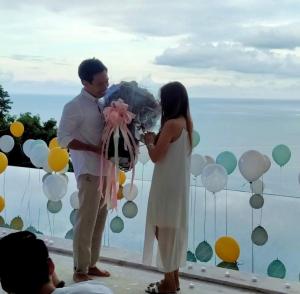 a man and a woman holding a bouquet in front of balloons at BelVillas-Award Winning SeaView Luxury Villas in Chaweng