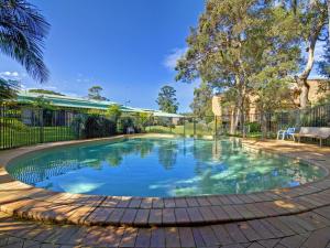 a swimming pool in a yard with a fence and trees at Bay Parklands 28 pool tennis court and stunning views in Shoal Bay