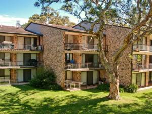 an apartment building with balconies and a tree at Bay Parklands 32 fantastic unit with air conditioning pool tennis court and spa in Shoal Bay