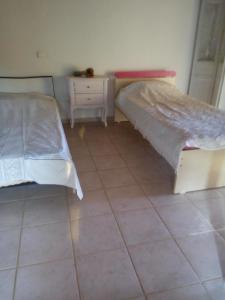 two beds in a room with a tiled floor at Εξοχικό σπίτι ΚΑΝΤΗΡΑΚΑΣ in Gythio