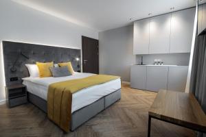 a bedroom with a large bed and a kitchen at Jono kalnelis Apartments in Klaipėda